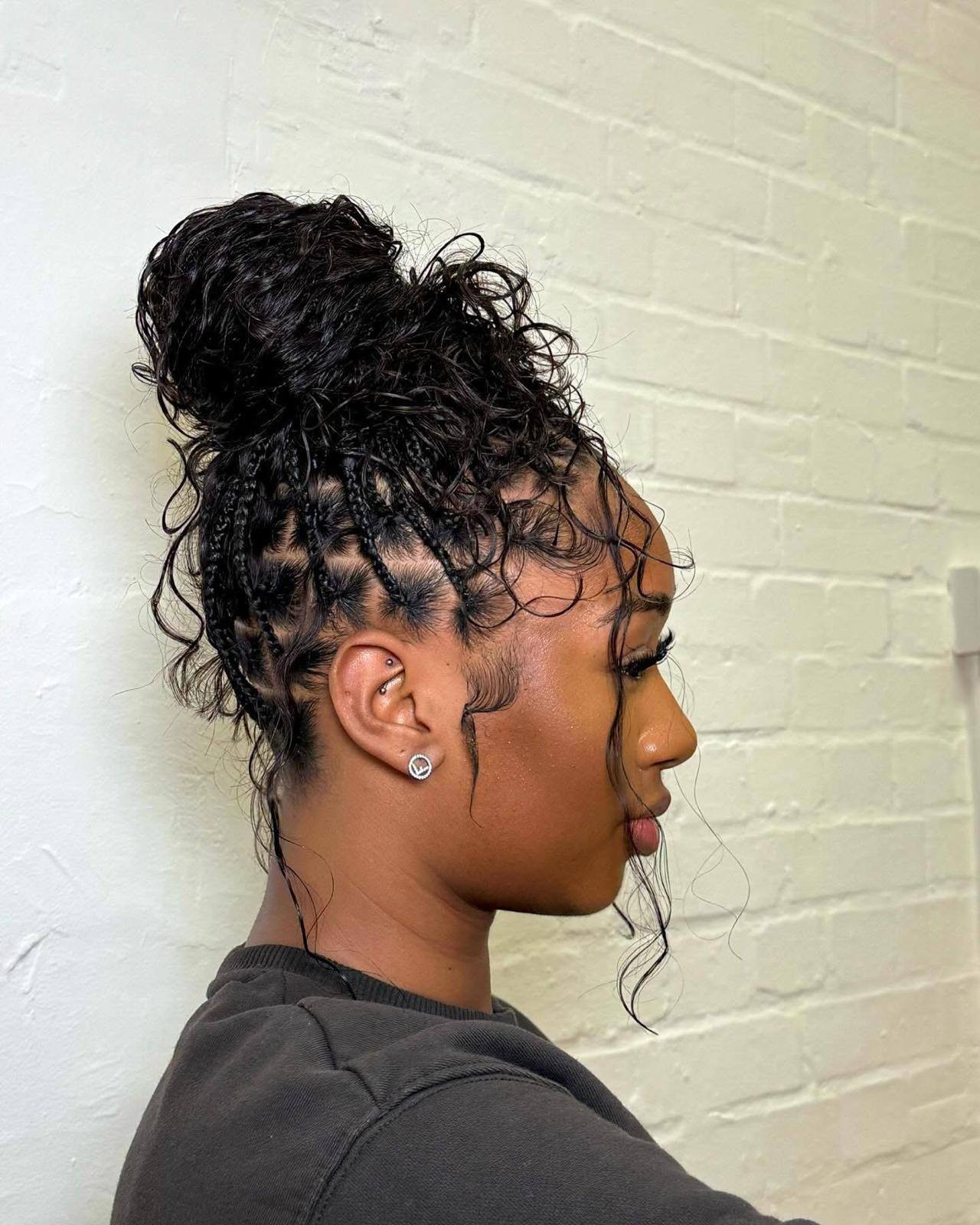 Braided updo with a curly bun, side profile